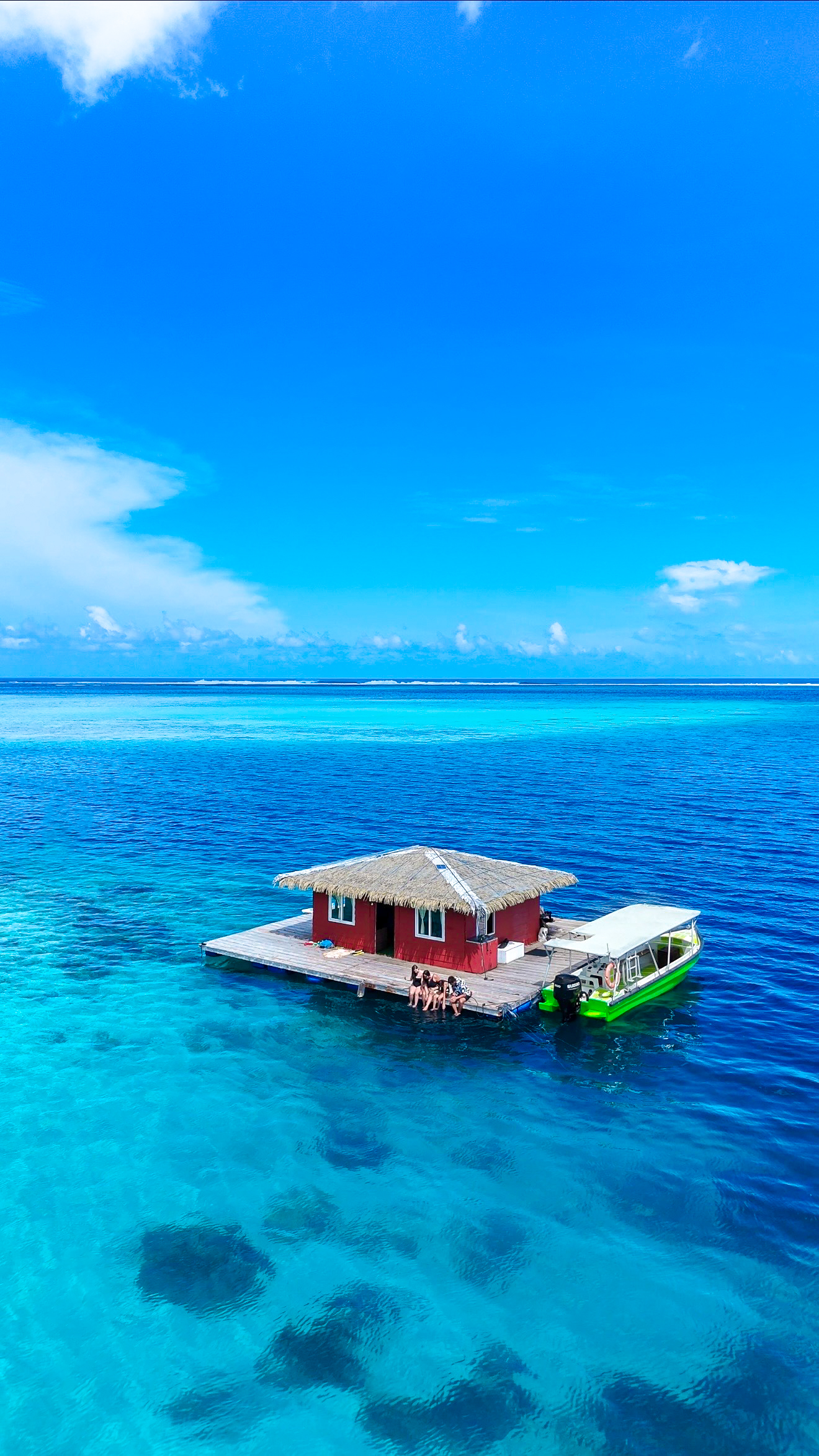 Salty Vagabonds family sitting on a floating pearl farm house over turquoise water in Tahiti, French Polynesia